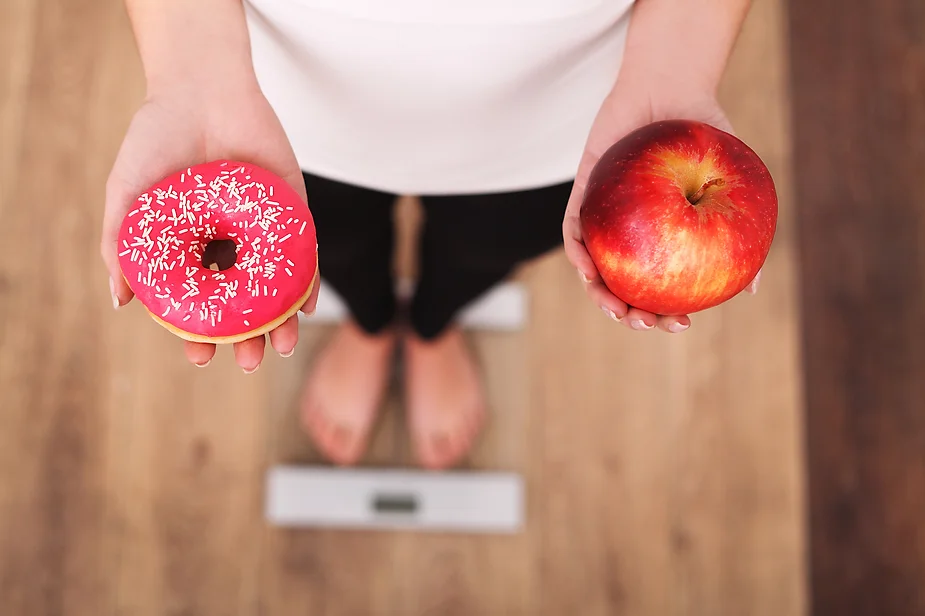 a person holding a donut and an apple