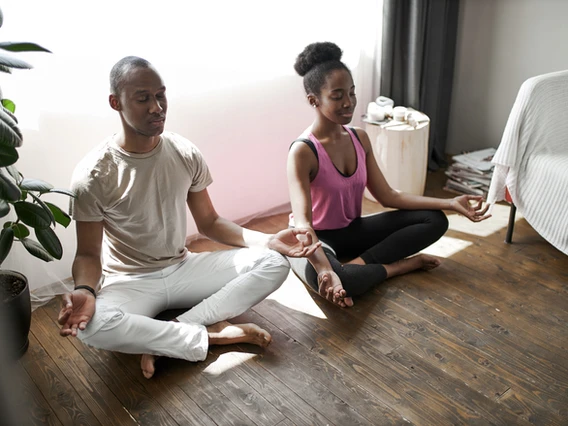 a man and woman sitting on the floor with their hands in the air