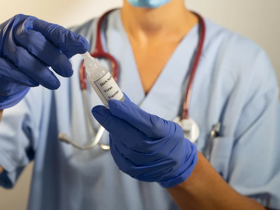 a doctor holding a vial of vaccine